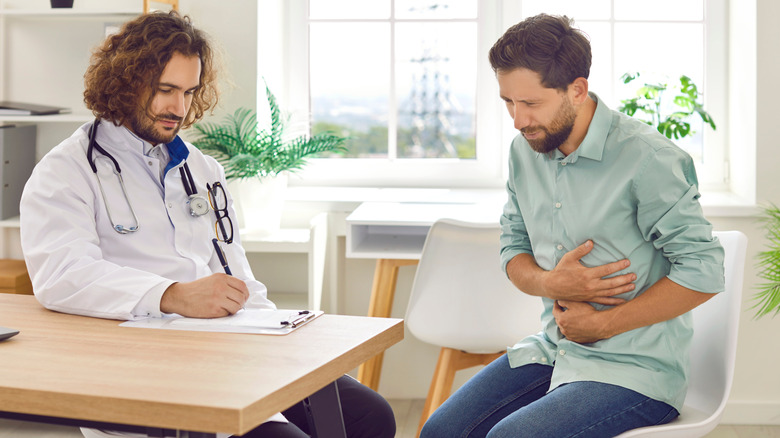 doctor helping patient struggling with stomach pain