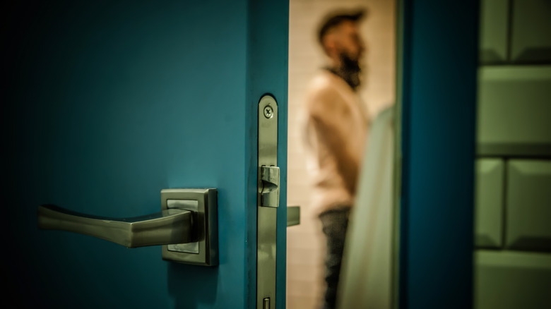 Open door showing blurred man peeing