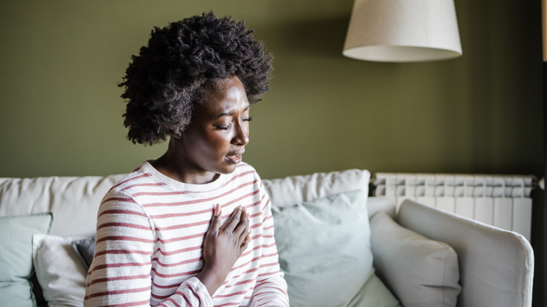woman holding her chest while breathing through her mouth