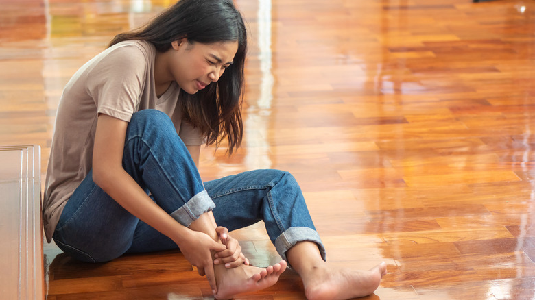 woman on floor holding foot in pain