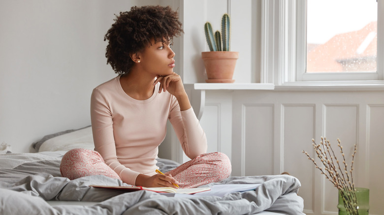 woman looking away reflectively while journaling