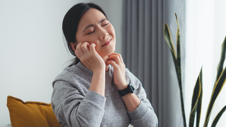 Woman scratching face and neck