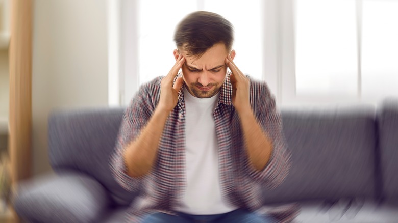 dizzy man sitting down holding his temples