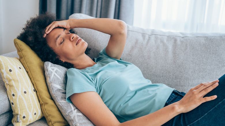 woman feeling dizzy while lying on the couch
