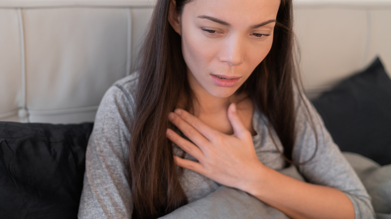 concerned woman holding chest in bed