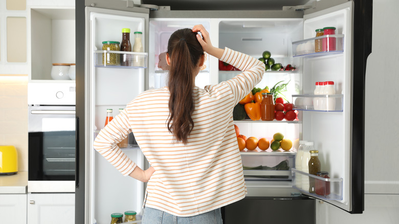 woman looking at her open refrigerator