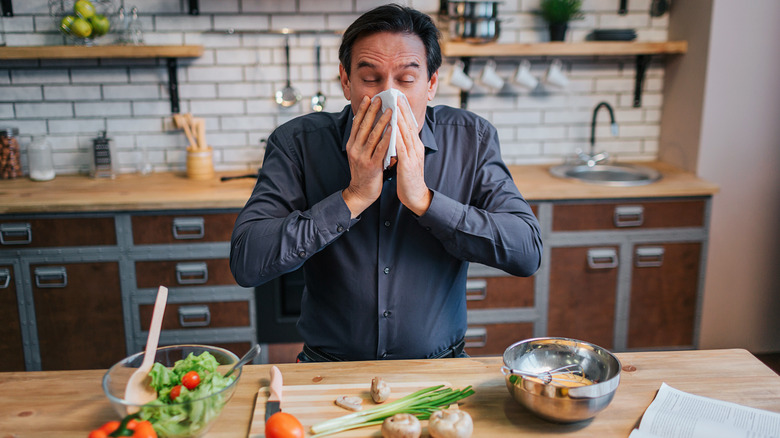 Man sneezing in kitchen