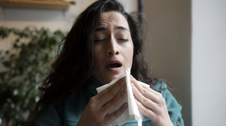 Woman sneezing into tissue