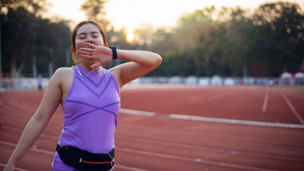 Young woman yawning while running