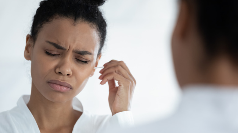 Woman cleaning ear with cotton swab