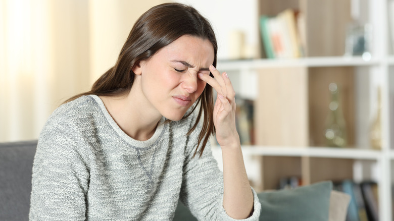 Wincing woman touching eye