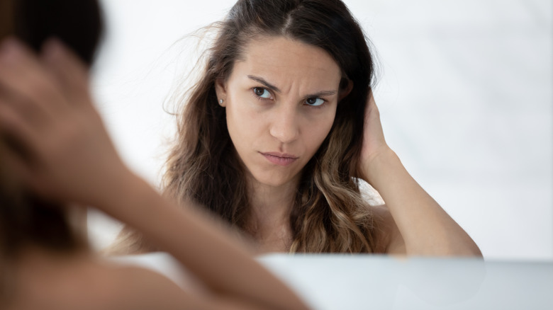 Woman looking in mirror with concern