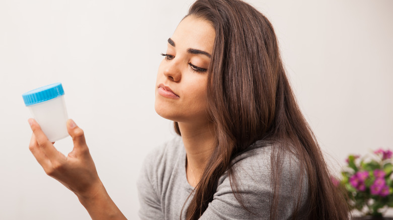 Woman holding urine sample cup