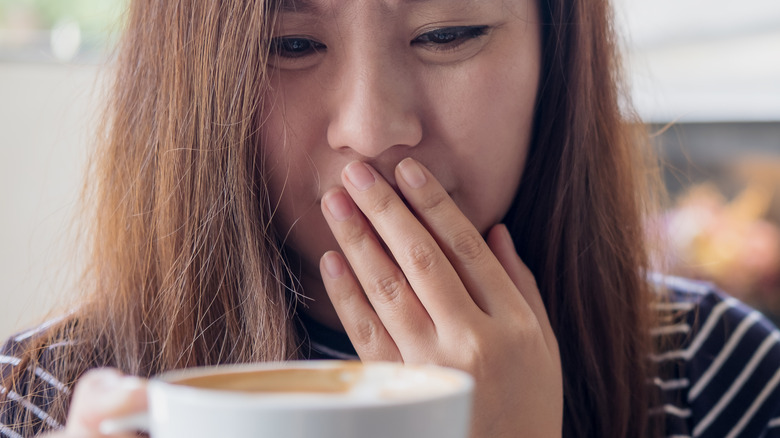 Puzzled woman staring at coffee mug