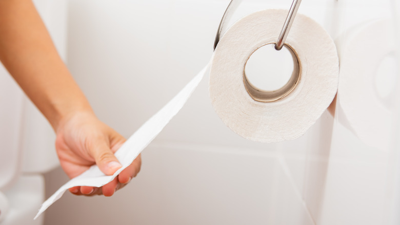 woman tearing off a piece of toilet paper