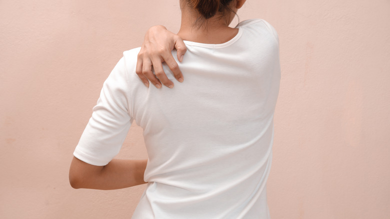 A woman scratching at her shoulder blade
