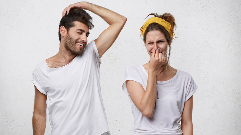 woman holds her nose as smelly man flirts