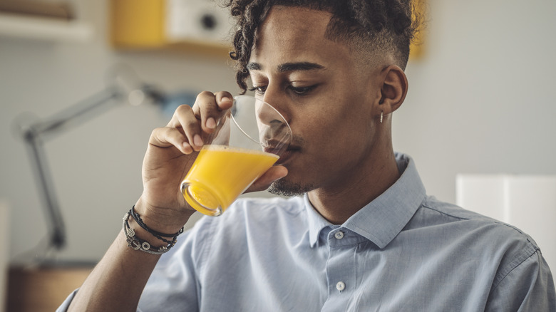 Man drinking glass of orange juice