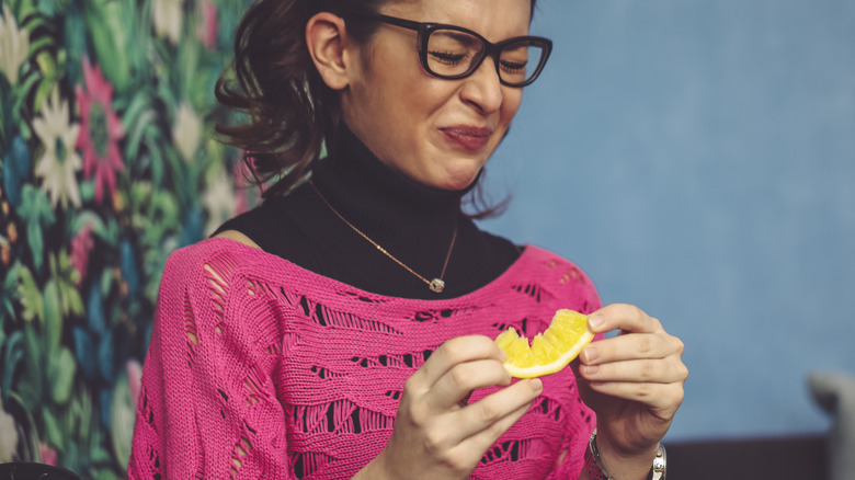woman wincing while eating sour lemon