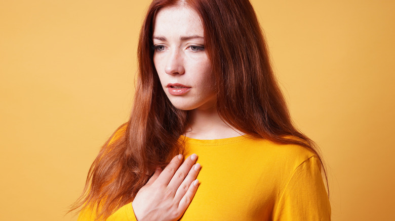 Woman in yellow experiencing heartburn 
