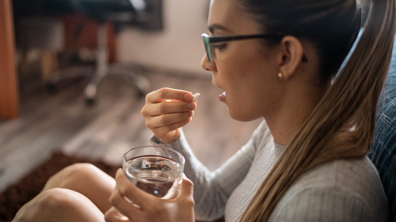 A woman tries to swallow a pill at home