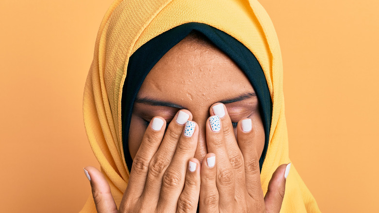Woman in hijab rubbing eyes
