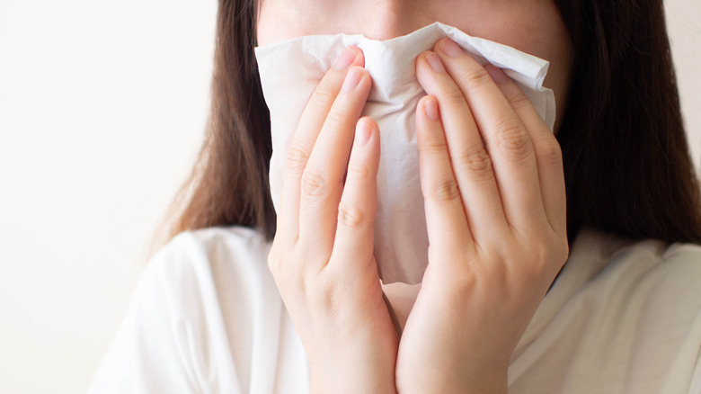 A woman sneezing into a tissue