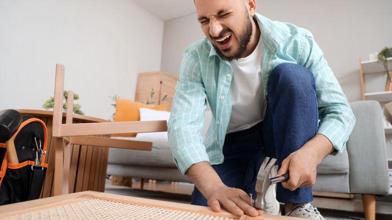 man hitting finger with hammer by accident