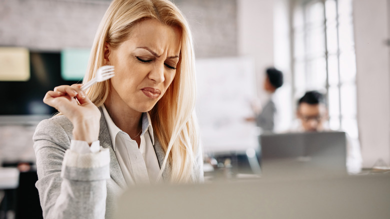 Woman doesn't like the taste of the food she is eating.