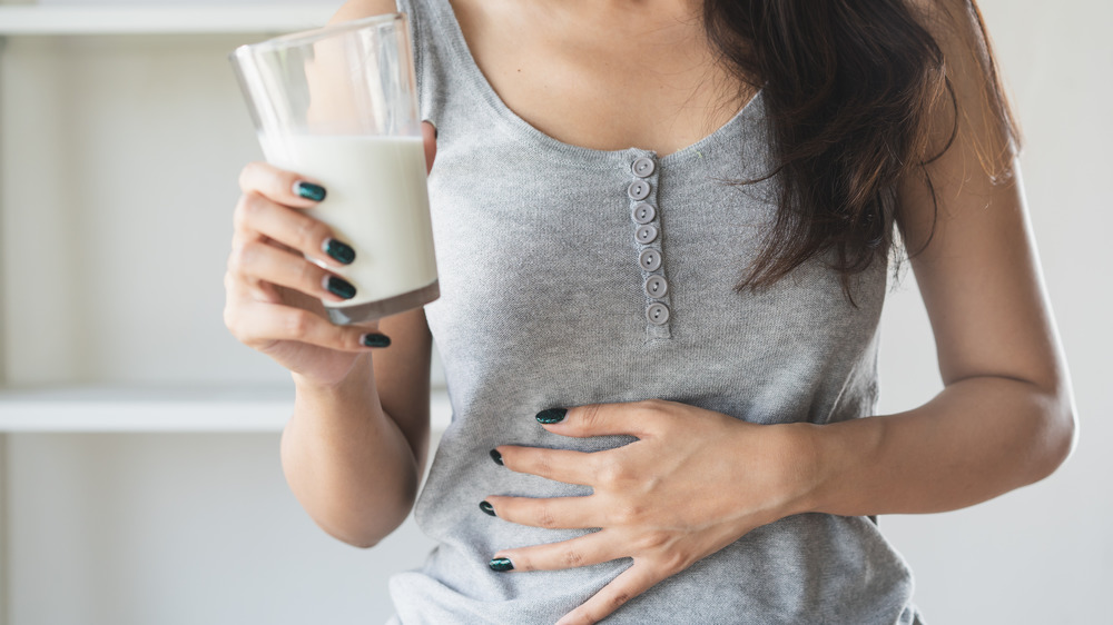 Woman holding a glass of milk with stomachache 