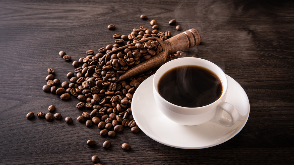 Cup of black coffee with coffee beans on the table