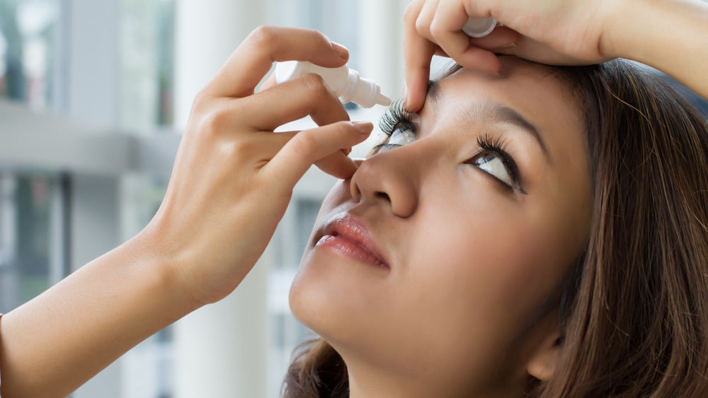 Woman putting eye drops in her eye