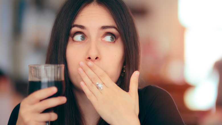 Woman embarrassed by hiccups while drinking wine