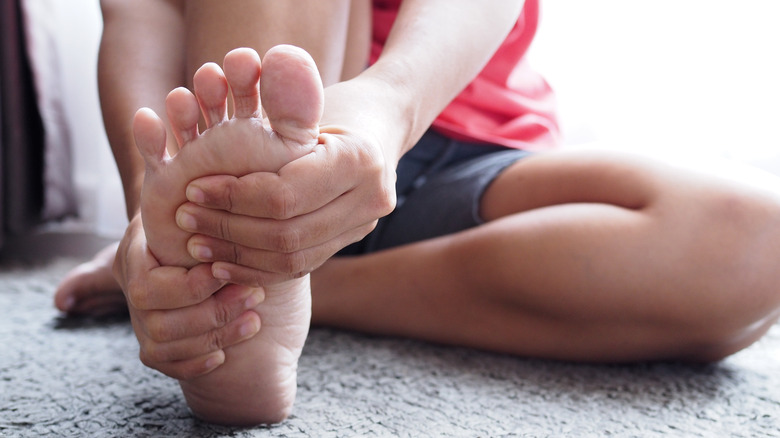 woman massaging foot while stretching