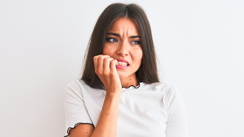 Concerned young woman biting nails