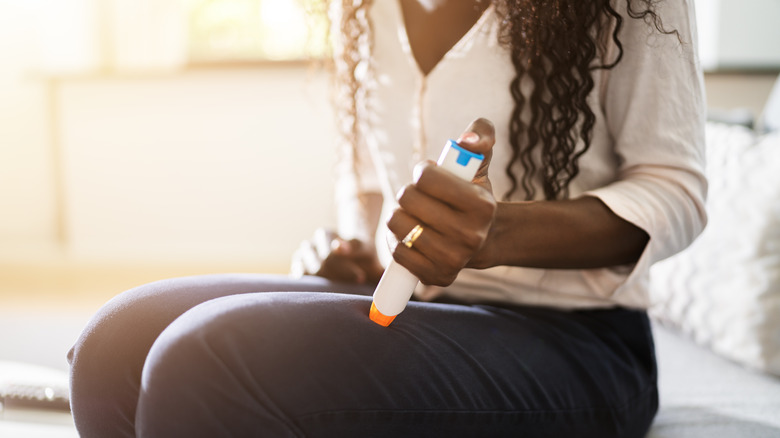 Woman injecting epipen in thigh