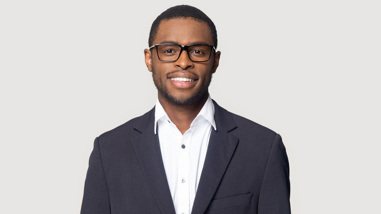 Smiling businessman with glasses on grey background 