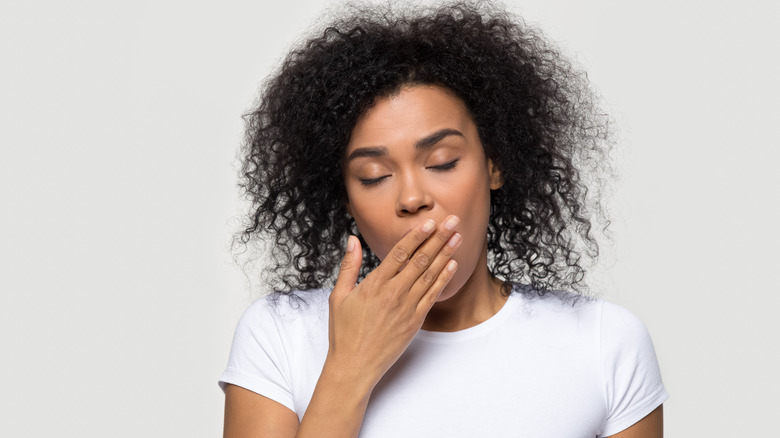 Tired woman yawning with hand over mouth