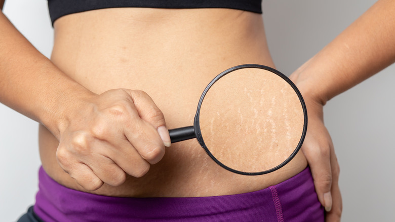 Woman holding magnifying glass to stomach