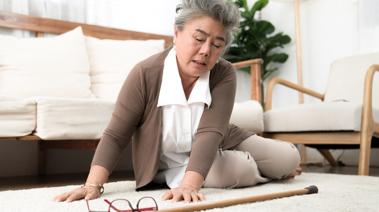 An elderly woman has a hard time getting up from the floor