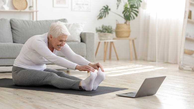An elderly woman stretches on the floor