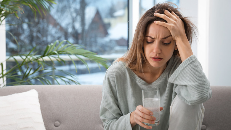 Woman with hangover holding glass of water 