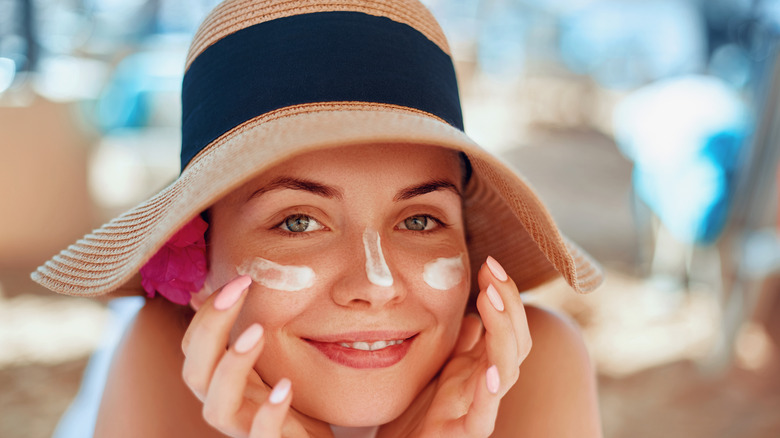 Woman wearing sunscreen and hat at beach