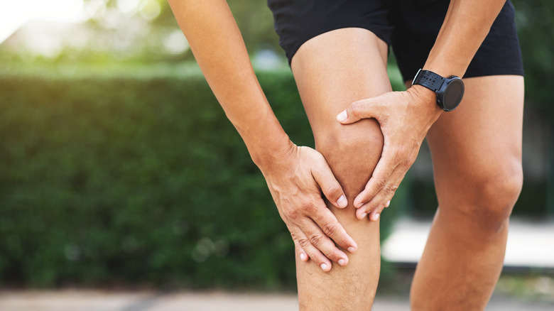 Close up of male athlete holding his knee in pain