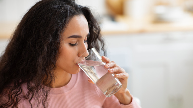 A woman drinks a glass of water