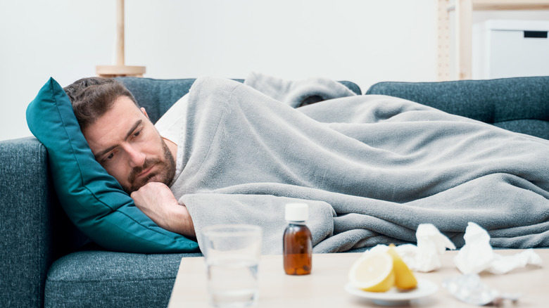 A man lies on the couch with a cold