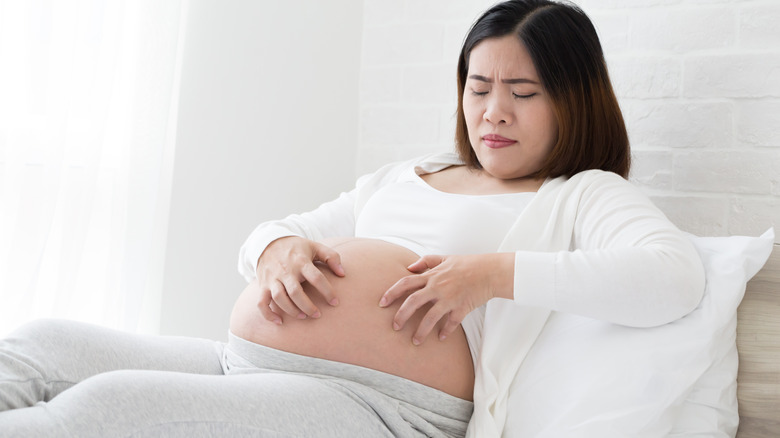 Pregnant woman scratching belly