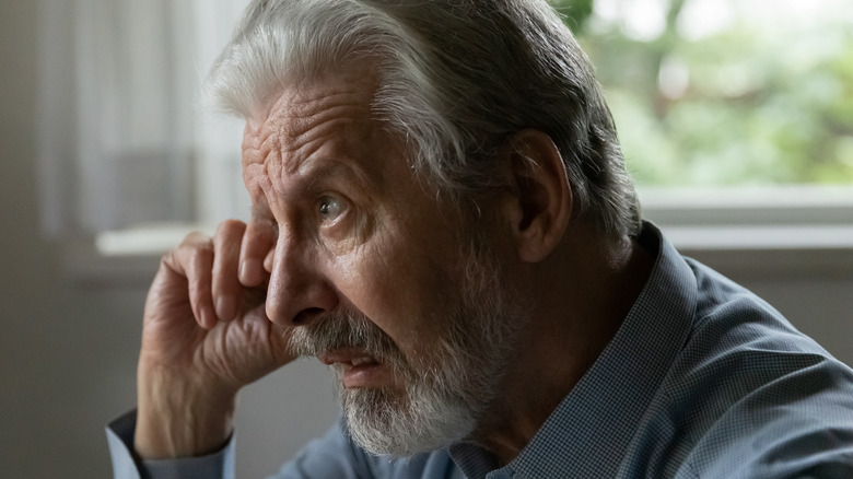 Older man rubbing his eye