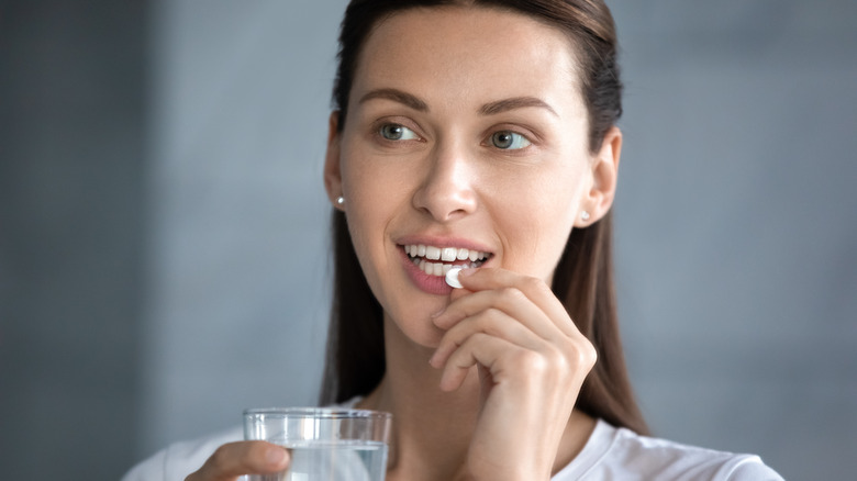 A woman takes a vitamin