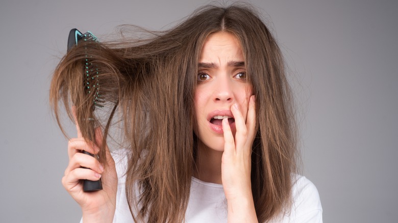 Distressed woman brushing frizzy hair